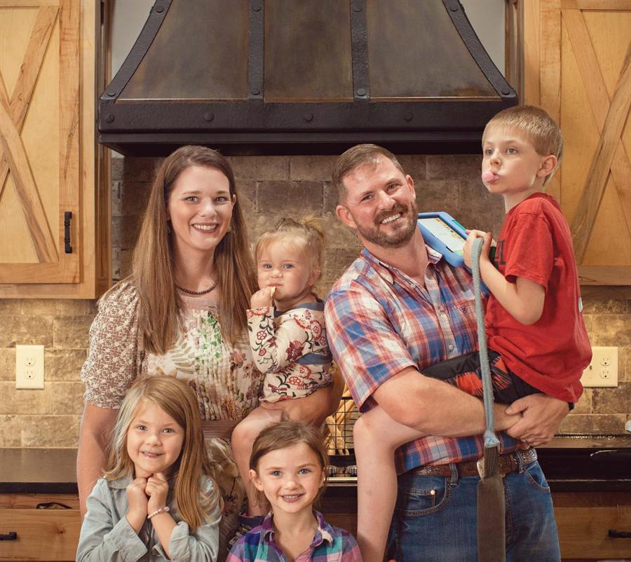 Adults and children posing indoors in front of a fireplace